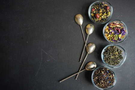 Different types of tea, green tea, peony and ginger tea, rose bud and wild flowers tea on dark wooden background with copyspaceの写真素材