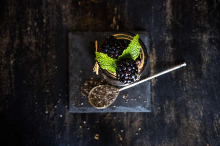 Fresh organic blackberries with mint and ice as a summer dessert concept on dark rustic table with copyspaceの写真素材