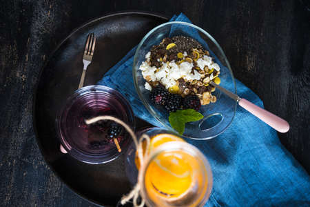 Oatmeal with chia and blackberries as a organic breakfast concept and detox drink of blackberries and lemon on dark rustic tableの写真素材