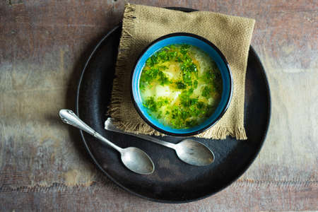 Healthy soup with rice and herbs in vintage bowl on old wooden tableの写真素材