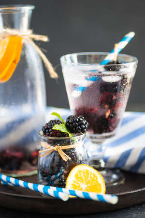 Detox lemonade with fresh organic blackberries and lemon on dark wooden table with copyspaceの写真素材