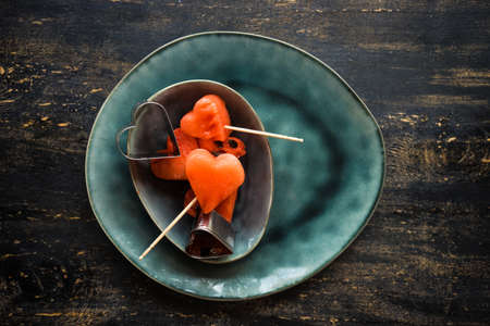 Organic sweet watermelon heart shaped pieces on vntage plate decorated with mint on rustic wooden table with copyspaceの写真素材