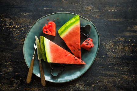 Organic sweet watermelon heart shaped pieces on vntage plate decorated with mint on rustic wooden...