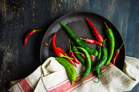 Organic chilli peppers on a pan on dark wooden background with copyspaceの写真素材