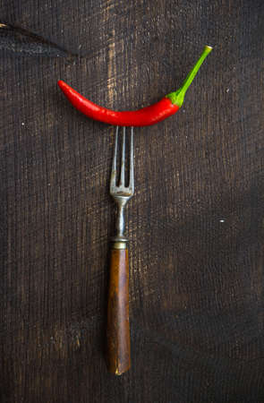 Organic chilli peppers on a pan on dark wooden background with copyspaceの写真素材