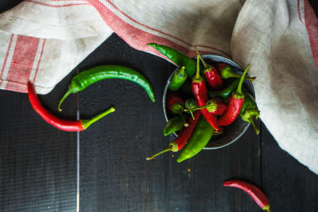 Organic chilli peppers on a pan on dark wooden background with copyspaceの写真素材