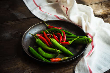 Organic chilli peppers on a pan on dark wooden background with copyspaceの写真素材