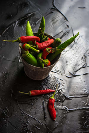 Organic chilli peppers on a pan on dark wooden background with copyspace