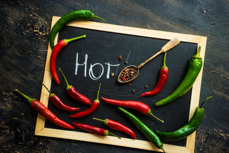 Organic chilli peppers on a pan on dark wooden background with copyspace
