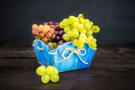 Fresh organic autumnal grapes on rustic plates on old wooden table with copyspaceの写真素材