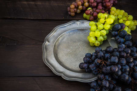 Fresh organic autumnal grapes on rustic plates on old wooden table with copyspaceの写真素材