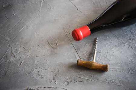 Old vintage corkscrew and bottle of red wine on dark wooden tableの写真素材