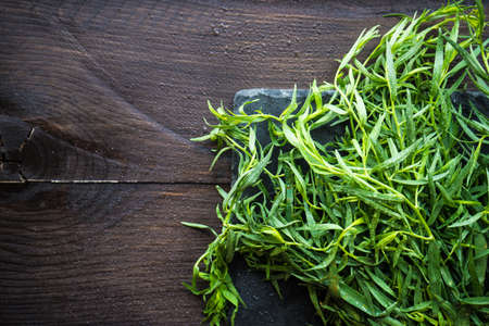 Tarragon herb as a organic salad ingredient on dark wooden tableの写真素材