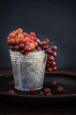 Fresh organic autumnal grapes on rustic plates on old wooden table with copyspaceの写真素材