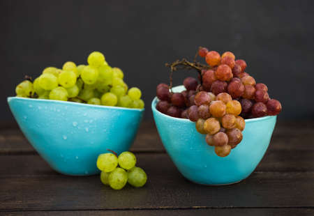 Fresh organic autumnal grapes on rustic plates on old wooden table with copyspaceの写真素材