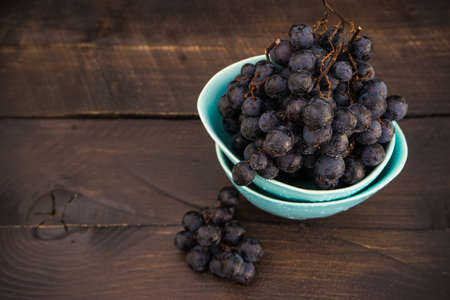 Fresh organic autumnal grapes on rustic plates on old wooden table with copyspaceの写真素材