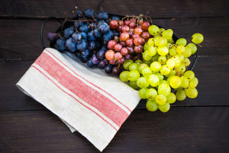 Fresh organic autumnal grapes on rustic plates on old wooden table with copyspaceの写真素材