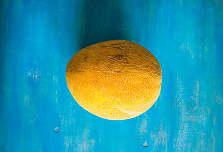 Organic summer melon on bright blue wooden table with copyspaceの写真素材