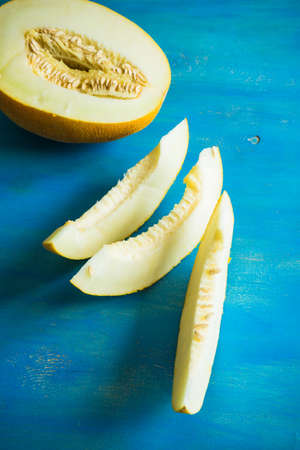 Organic summer melon on bright blue wooden table with copyspaceの写真素材
