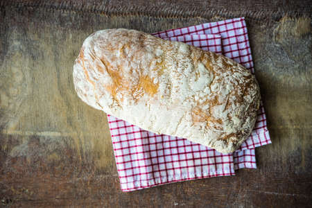 Fresh baked italian bread - ciabatta  on rustic table with napkin