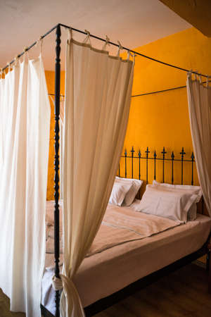 Old styled king size bed in orange bedroomの写真素材