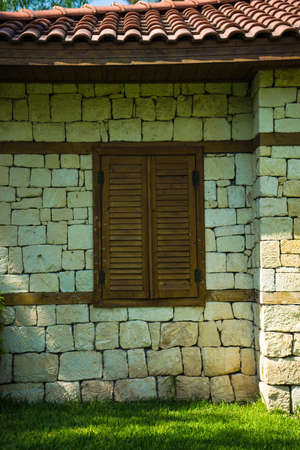 Beautiful brick house with shutters on a window and tropical garden