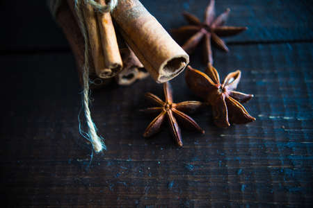 Christmas spices lika an anise star, cinnamon sticks and nuts on dark wooden tableの写真素材