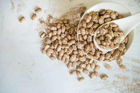 beans in a bowl ready to cook on white rustic wooden table with copyspaceの写真素材