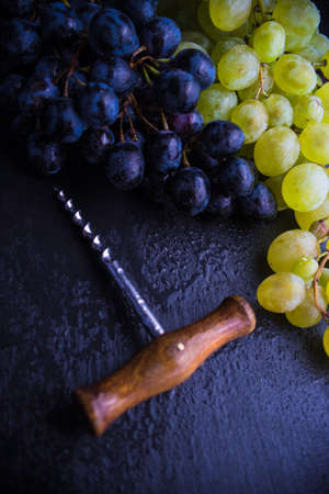 Organic ripe grape and vintage corkscrew on rustic background as a wine conceptの写真素材