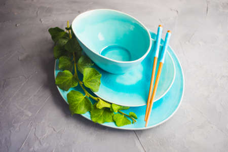 Rustic table setting with vintage ceramic plates, asian chopsticks and branch of ivy plant on dark old wooden table with copyspaceの写真素材
