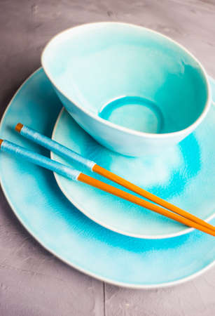 Rustic table setting with vintage ceramic plates, asian chopsticks and branch of ivy plant on dark old wooden table with copyspaceの写真素材