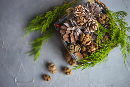 Christmas concet with busket full of pine cones and christmas decorations on grey concrete backgroundの写真素材
