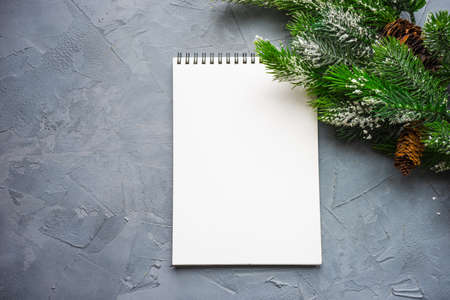 Christmas festive concept with notepad and christmas tree branch and decoration on old wooden table with copyspaceの写真素材