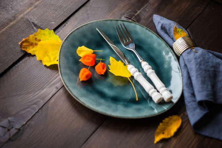 Autumnal table setting with bright yellow leaves and physalis  on old wooden table with copyspaceの写真素材