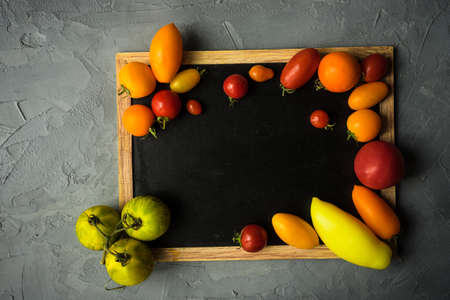 Organic food concept with different types of tomatoes on grey concrete background with copyspaceの写真素材