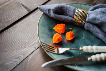 Autumnal table setting with bright yellow leaves and physalis  on old wooden table with copyspaceの写真素材