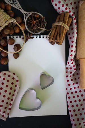 Cooking concept with cookies forms, napkin and notepad  on dark wooden table with copyspace
