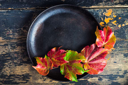 Festive autumnal table setting with bright red and yellow leaves with copyspaceの写真素材