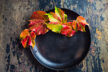 Festive autumnal table setting with bright red and yellow leaves with copyspaceの写真素材