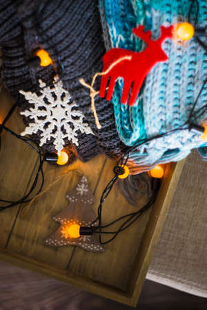 Christmas concept with scarfs and lights on wooden background
