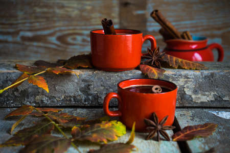 Autumnal concept with mup of coffee with spices, cinnamon stick and anise star on rustic wooden  background full of bright oak yellow leaves and acornsの写真素材