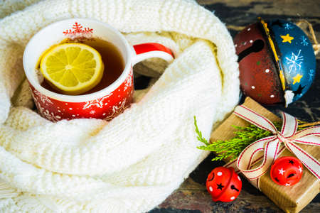 Red cup of tea with lemon, Christmas lights and decoration on rustic background with copyspaceの写真素材
