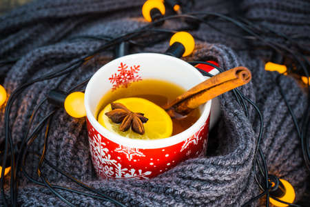 Red cup of tea with lemon, Christmas lights and decoration on rustic background with copyspaceの写真素材