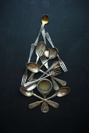 Christmas tree shaped with vintage silverware on dark wooden background as a holiday cooking concept