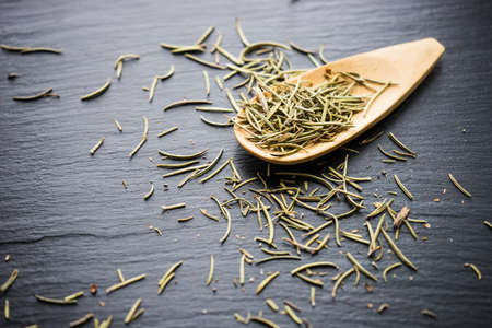 Fresh and dry rosemary spice on black stone board as a organic food conceptの写真素材