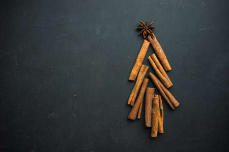 Christmas tree shaped with cinnamon sticks, anise star, and nuts on blackboard as a holiday concept