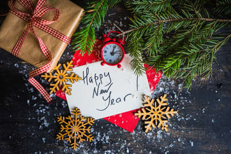 Holiday concept with Happy New Year text, decoration and  gift on dark wooden background