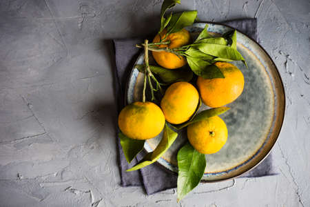 Christmas frame with fir tree branch, fresh tangerines  and holiday decorations on rustic backgroundの写真素材