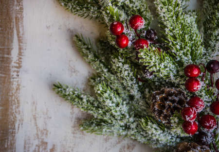 Christmas frame with fir tree branch, red berries and christmas tree shaped decoration on rustic...