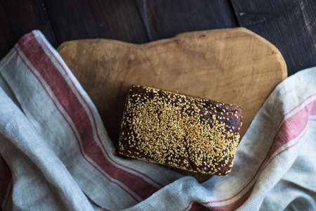 Tasty rye bread on cutting board on rustic wooden table